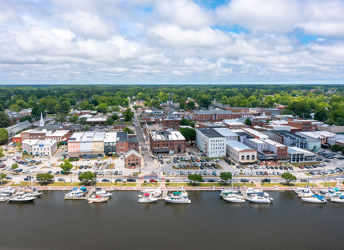 Washington, NC - Aerial View of Washington North Carolina with Commercial Buildings Next to the River and Boats on the Water on a Cloudy Day